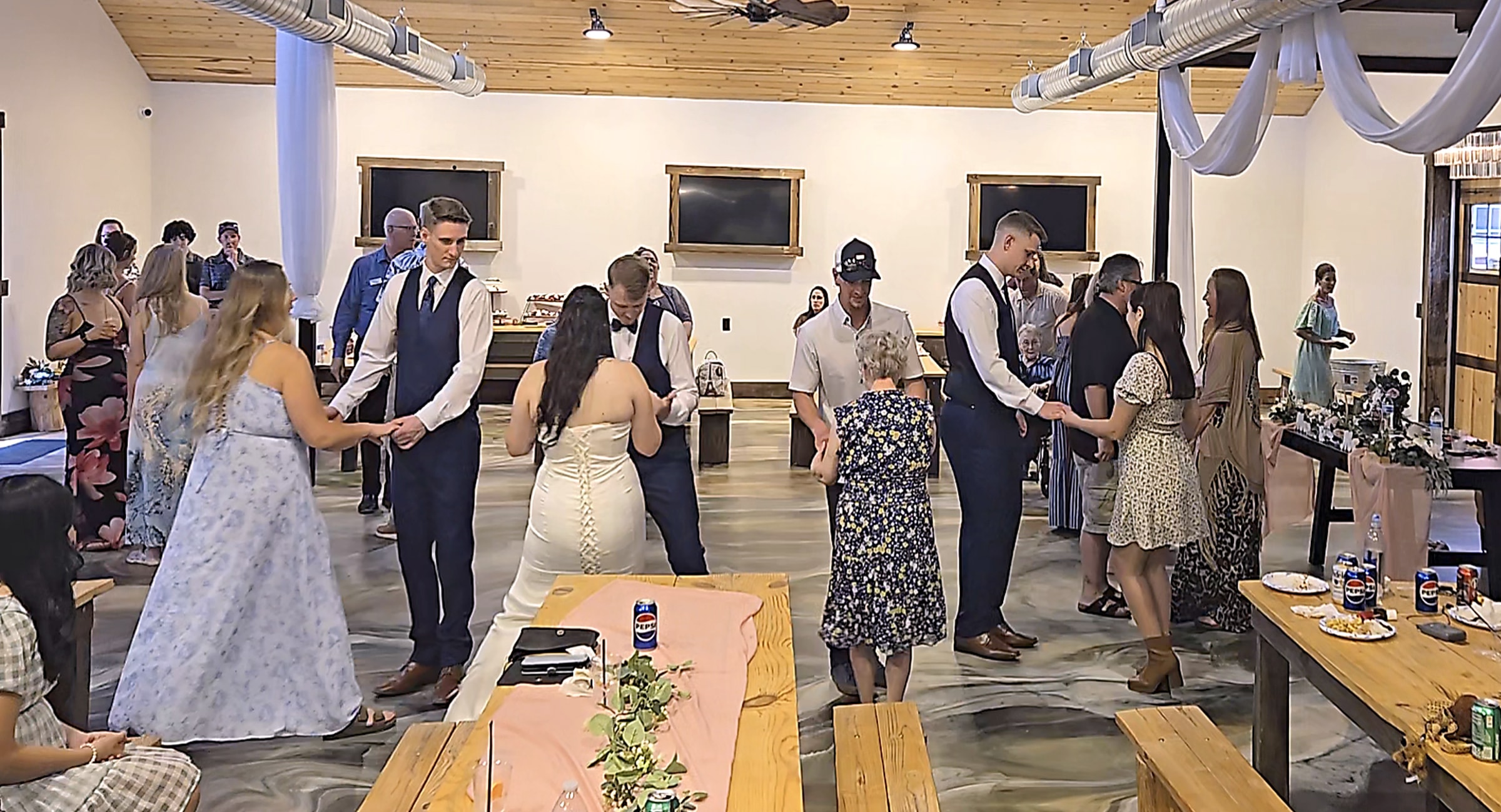 Wedding guests in formal attire doing a barn dance circle at a modern venue in Grants Pass, Oregon