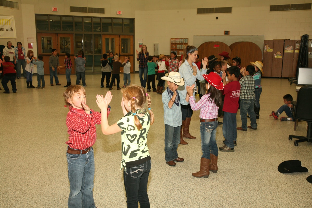 Students clapping and dancing in western attire during an in-school instruction program in Springfield, Arkansas