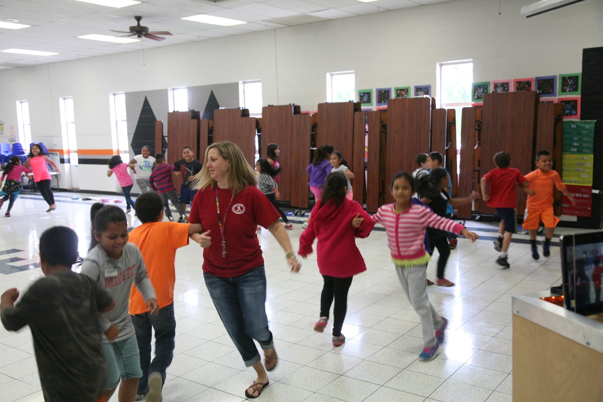 Teacher leading students in a folk dance activity in a gymnasium in Springfield, Arkansas